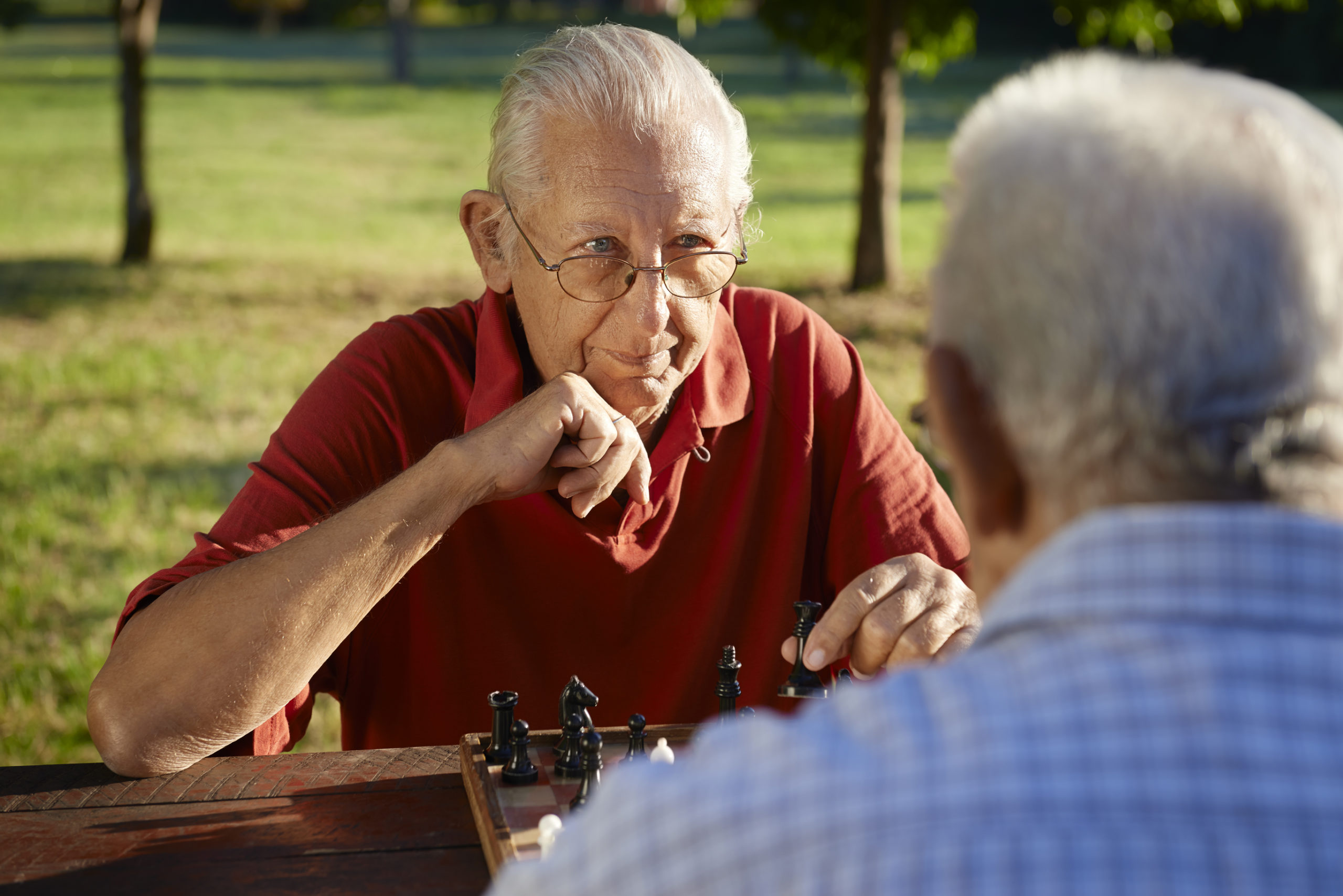 senior man playing chess in park