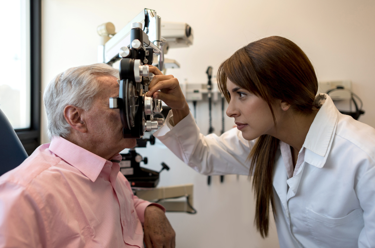 Female optometrist using a phoropter on senior patient at an eye clinic