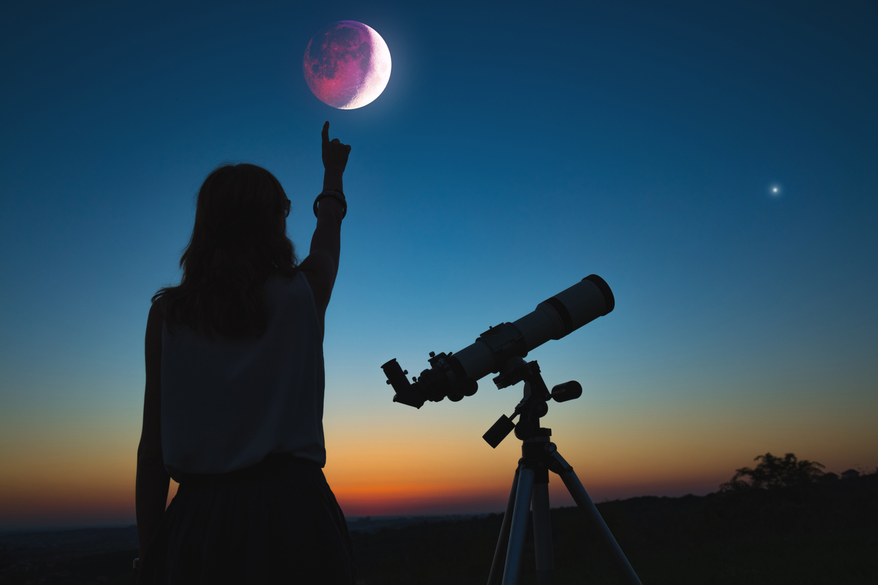 Girl looking at lunar eclipse through a telescope