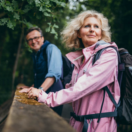 Older couple taking a break from a hike on a bridge