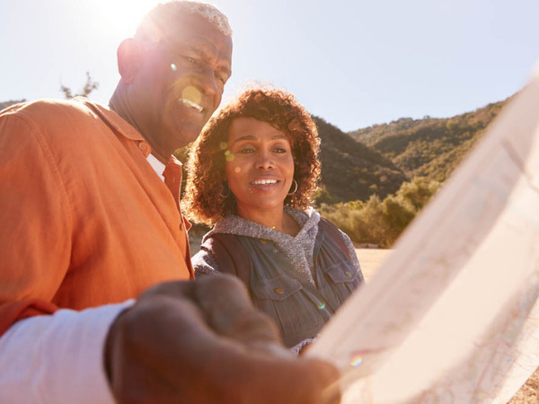 Older Black couple referencing a map during a mountain hike